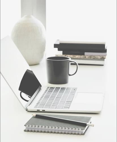 Laptop, mug, and notepad representing information gathering for outsourcing services.